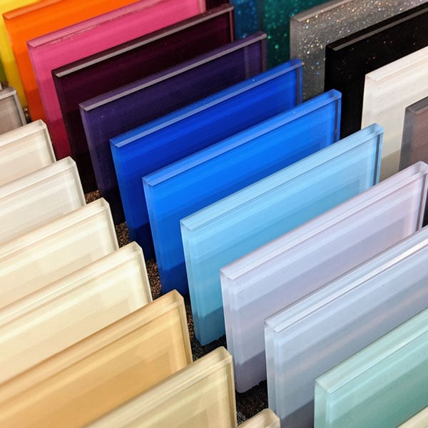 Kollektion von VSG-Glaslaminat-Mustern in zahlreichen Farben von Weiss ueber Blau und Rosa bis Schwarz aufgereiht