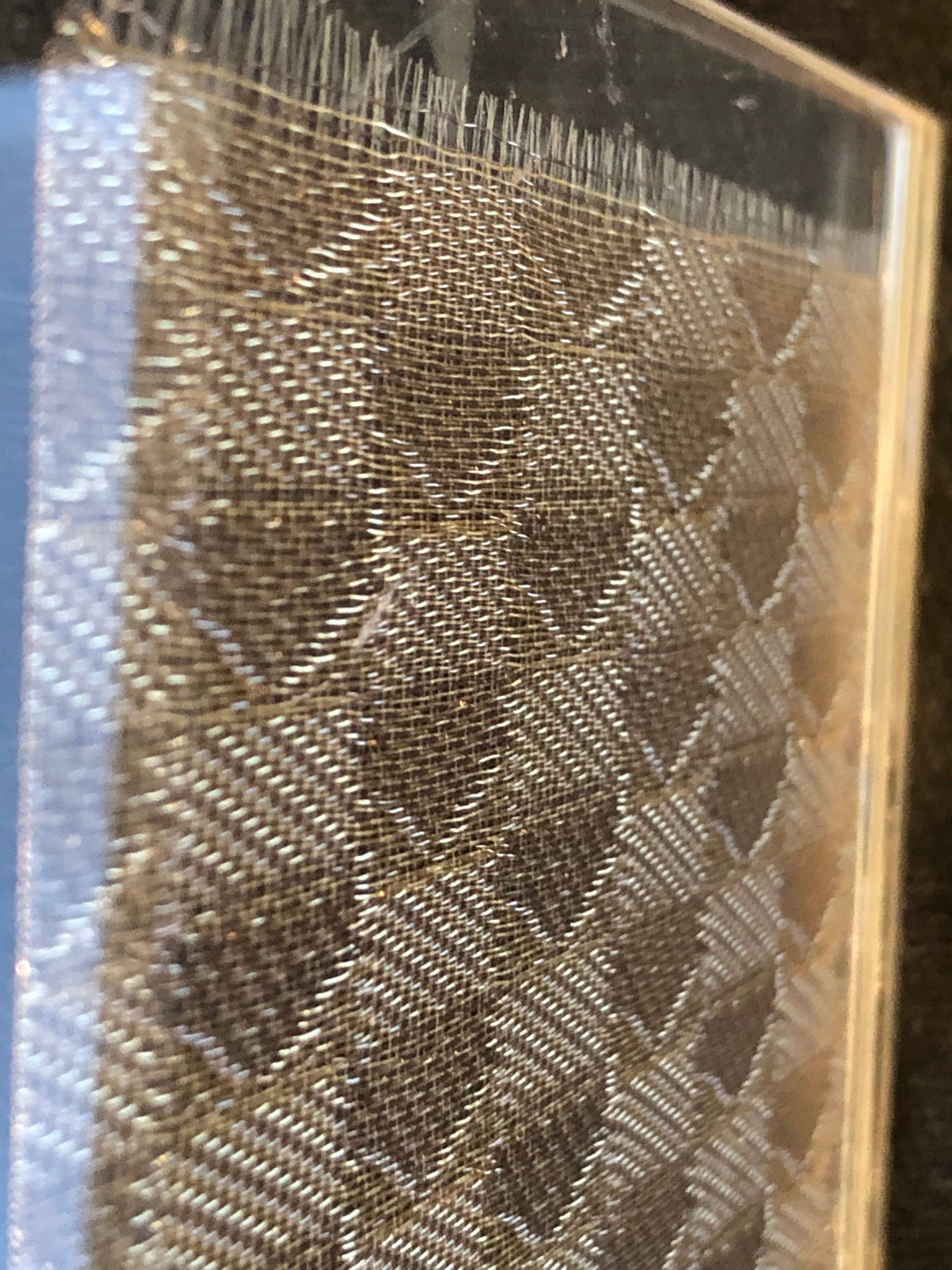 Nahaufnahme eines Glaslaminats mit einlaminiertem goldenen Metallgewebe im diagonalen Rautenmuster