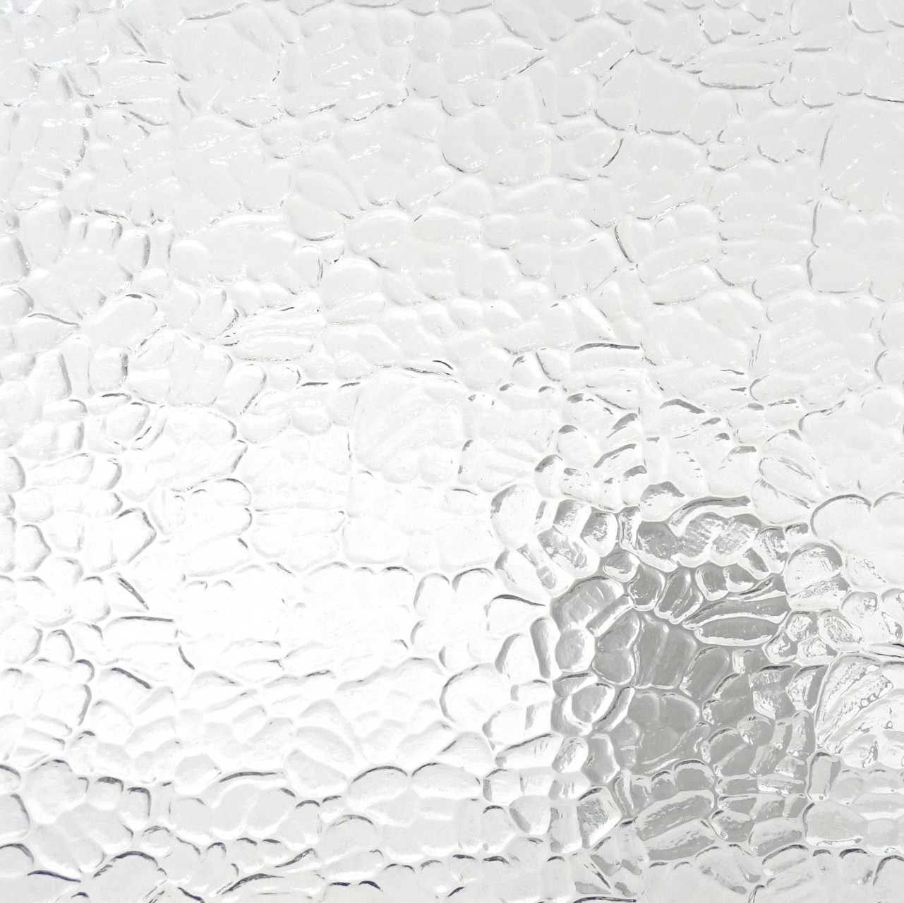 Reliefglas-Muster mit weisser Kieselstein-Struktur und wolkenartiger transparenter Oberflaeche in der Nahansicht