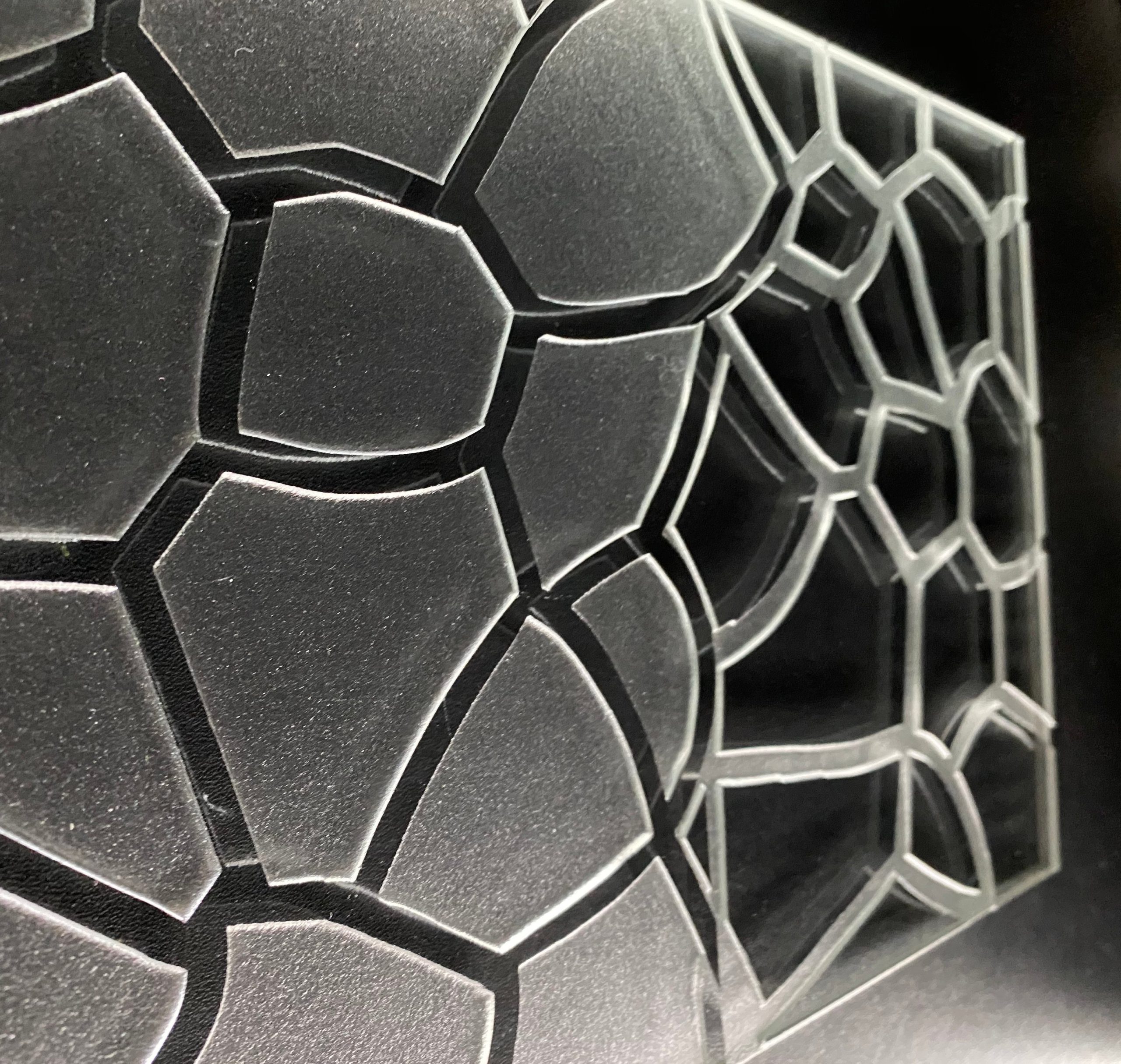 Reliefglas mit erhabener organischer Zellenstruktur im Voronoi-Muster in mattem Grau mit schwarzen Fugen