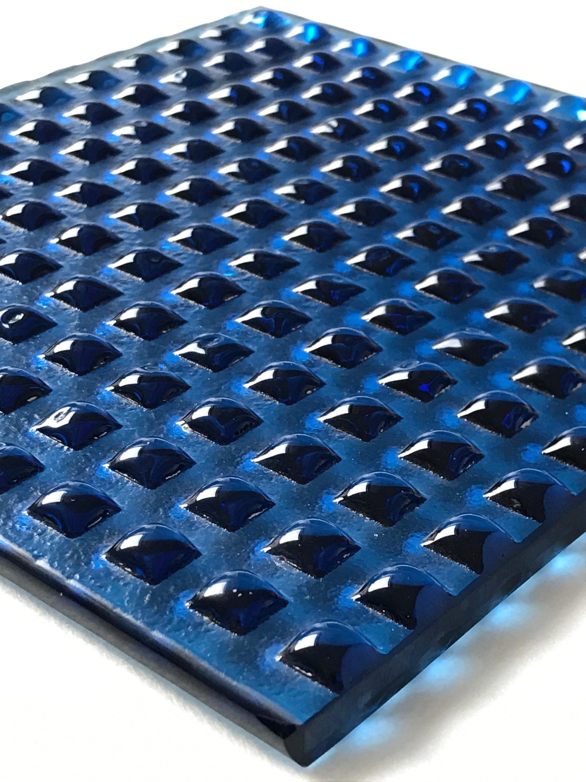 Dunkelblaue Schmelzglas-Platte mit gleichmaessigem Raster aus erhabenen Quadraten und glaenzender Oberflaeche