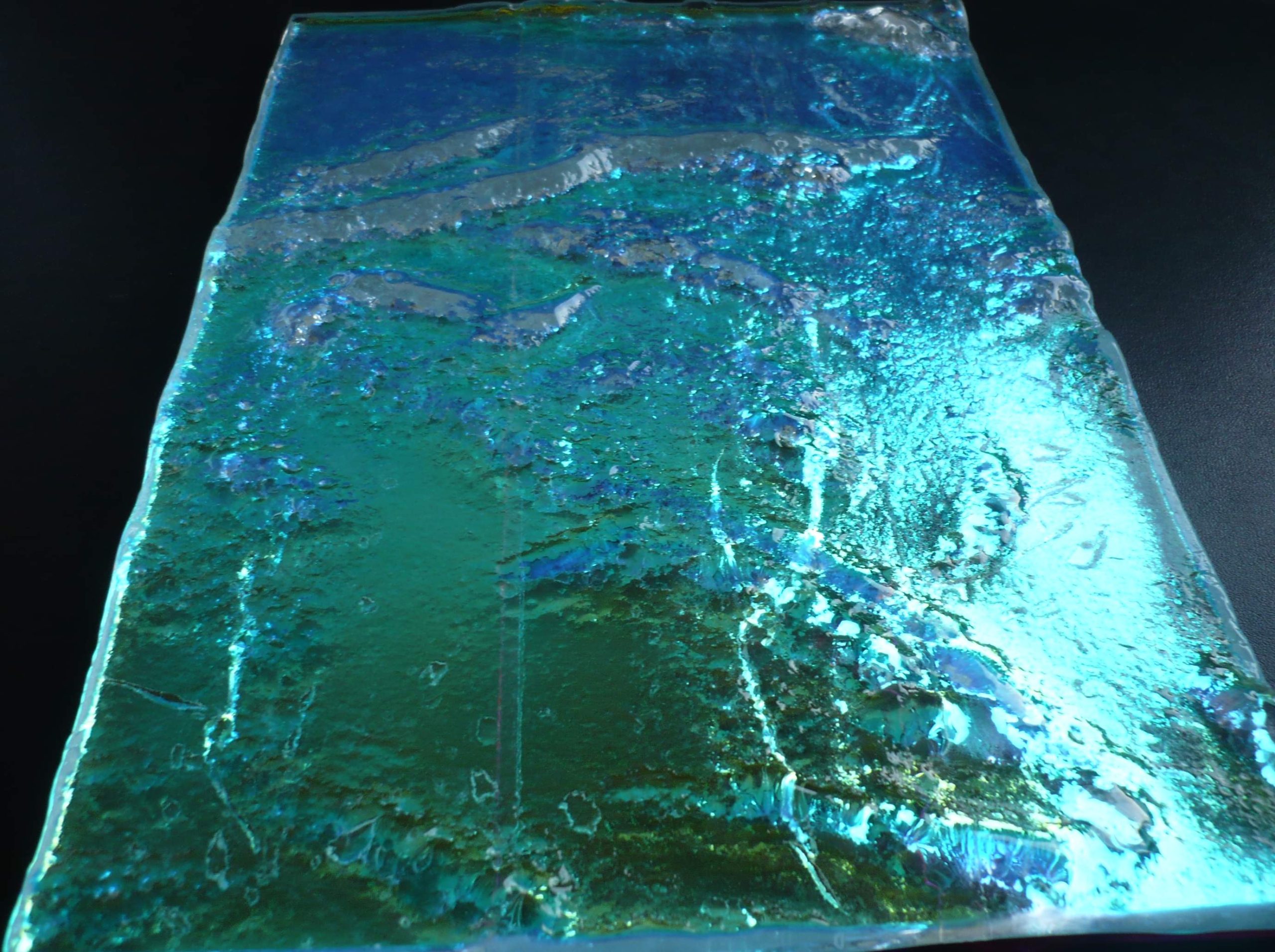 Schmelzglas-Platte in leuchtendem Tuerkis-Blau mit metallisch schimmernder Oberflaeche und Reliefstruktur